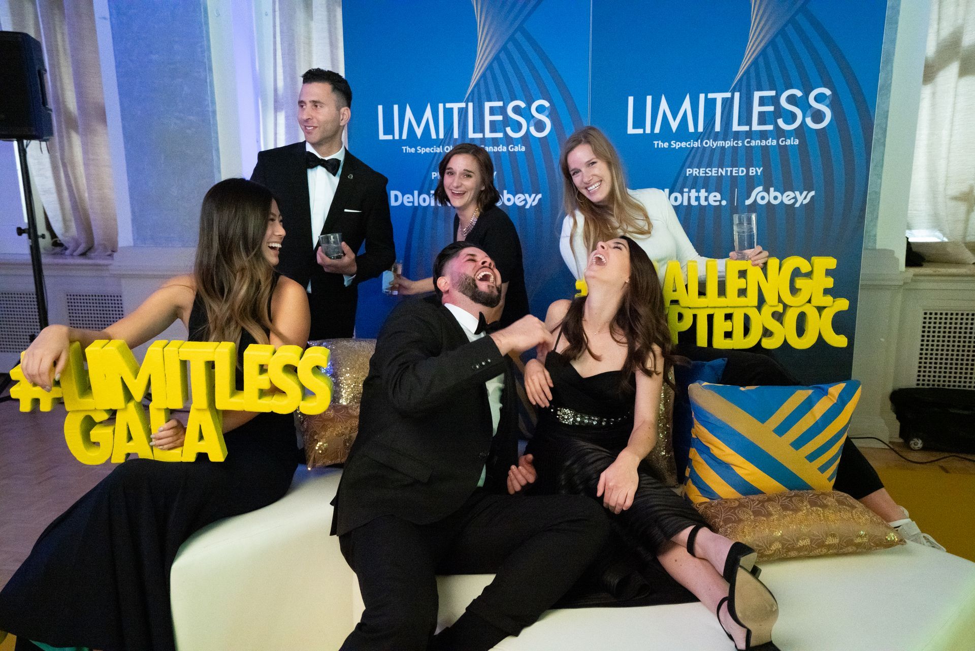 A group of people are posing for a picture in front of a sign that says limitless gala