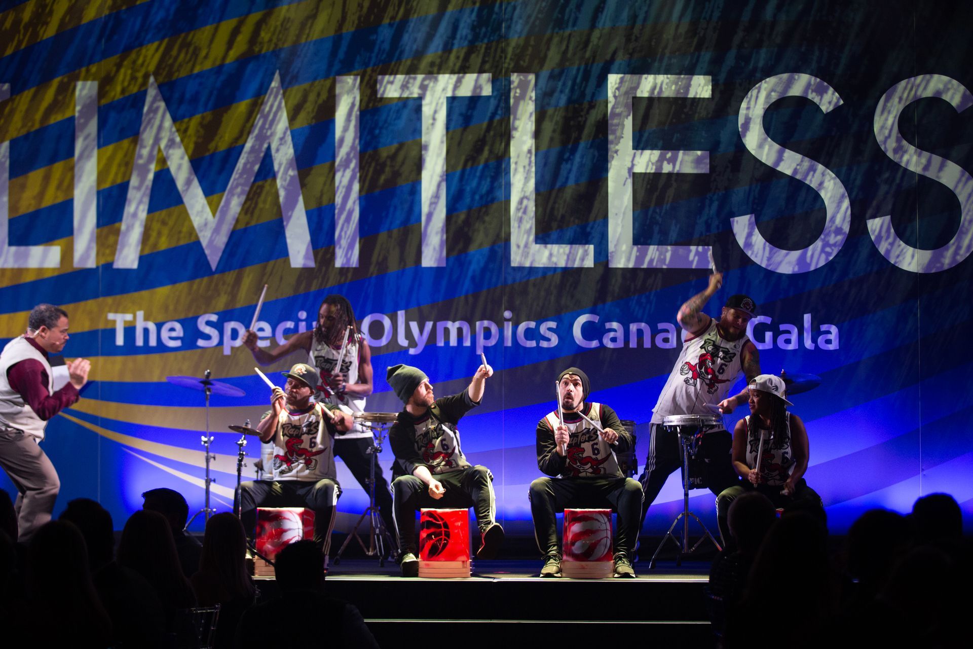 A group of people playing drums in front of a sign that says limitless
