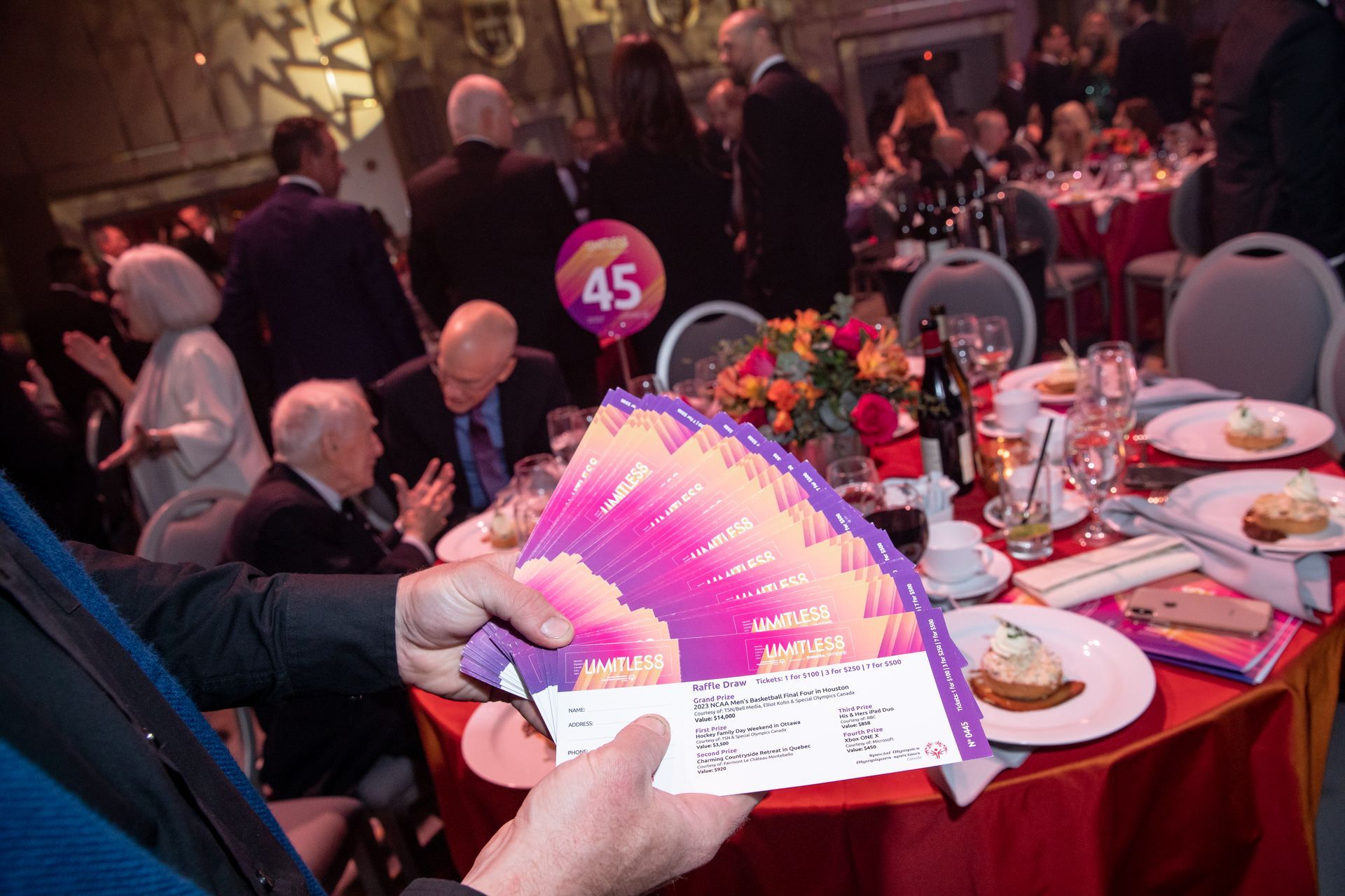 A person is holding a fan in front of a table with plates of food.