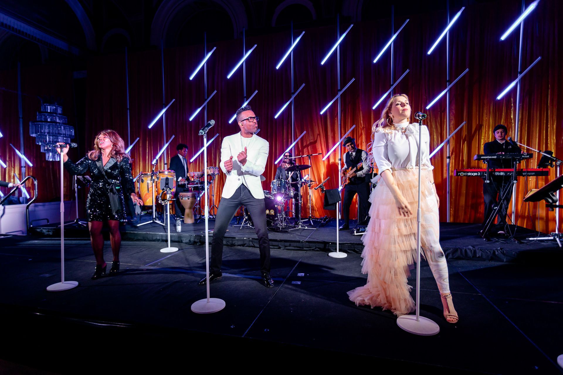 A group of people are singing into microphones on a stage.