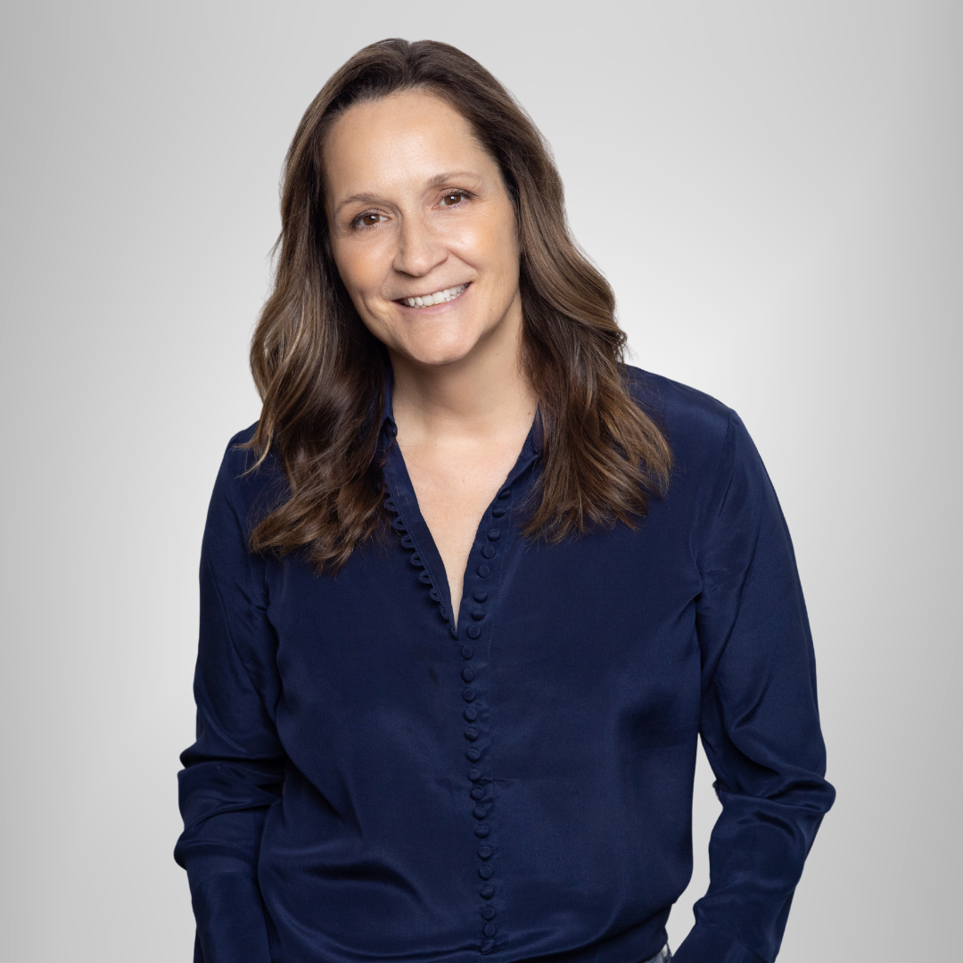 A woman in a blue shirt is smiling for the camera