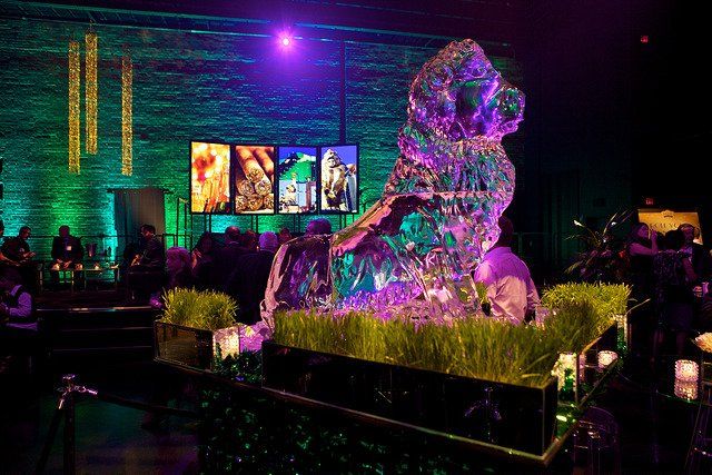 A large ice sculpture of a lion is sitting on top of a table in a dark room.