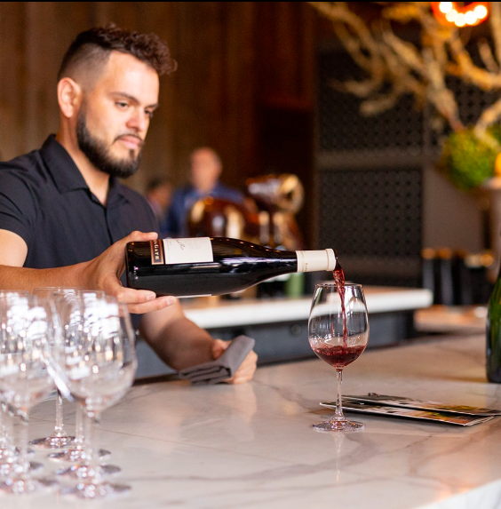 A man pouring a bottle of wine into a glass