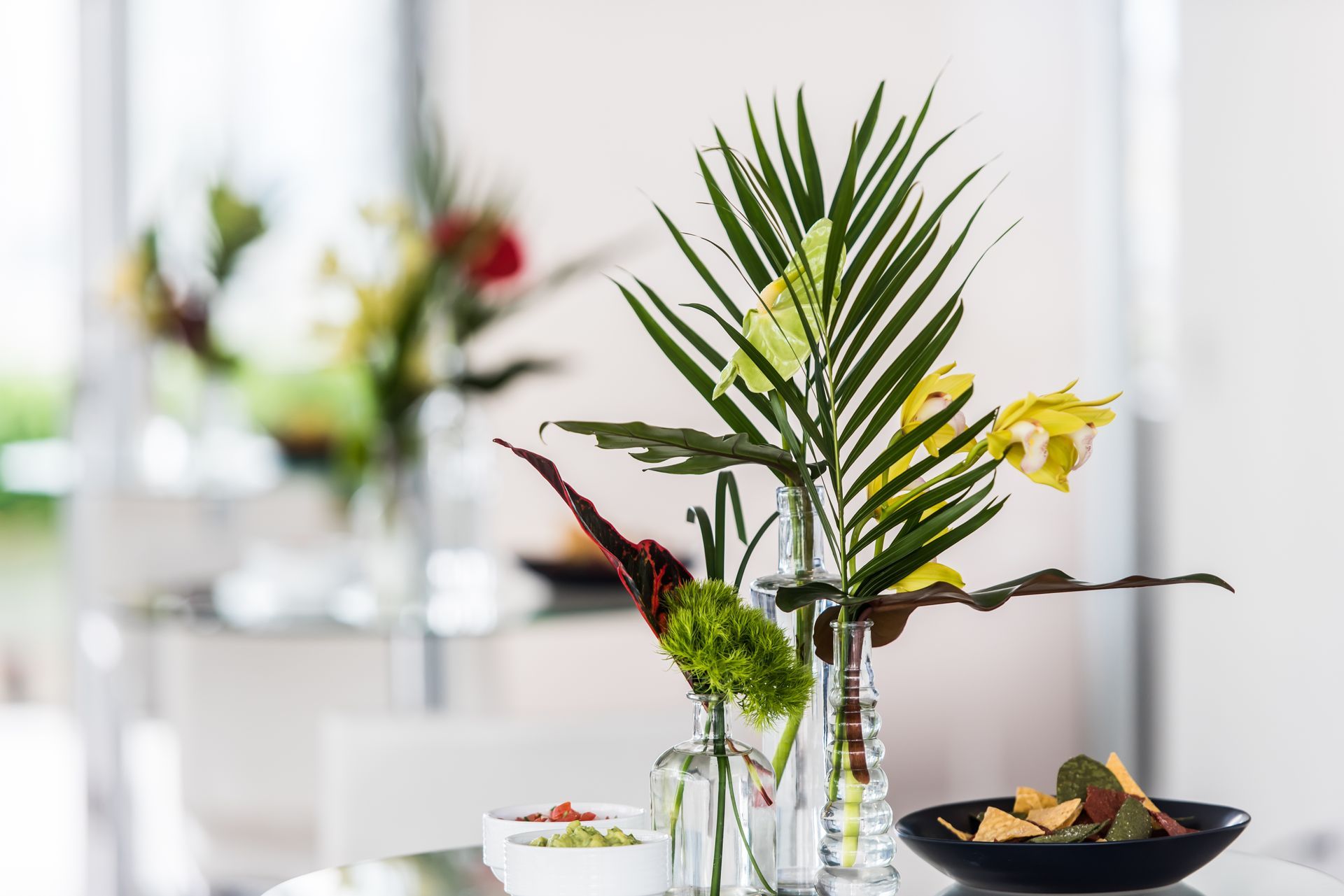 A table with a vase of flowers and a bowl of fruit on it.