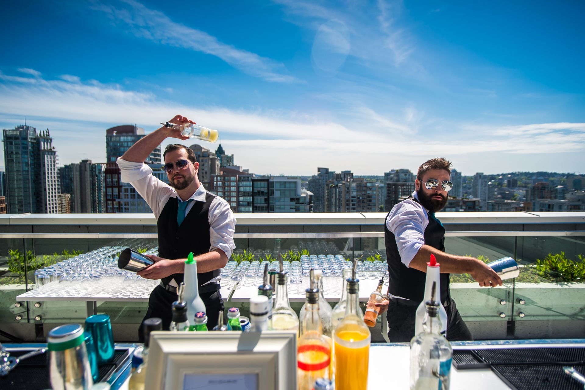 Two men are preparing drinks on a rooftop bar.