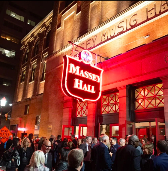 Massey hall is lit up at night with people gathered outside