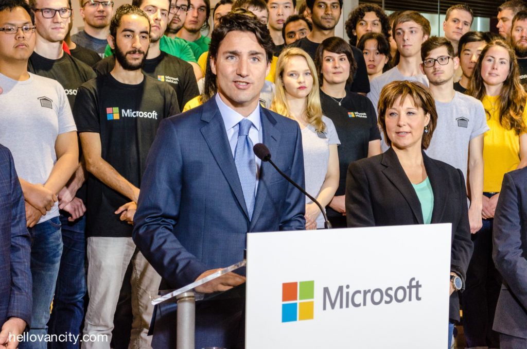 A man in a suit and tie is standing at a podium in front of a crowd of people.