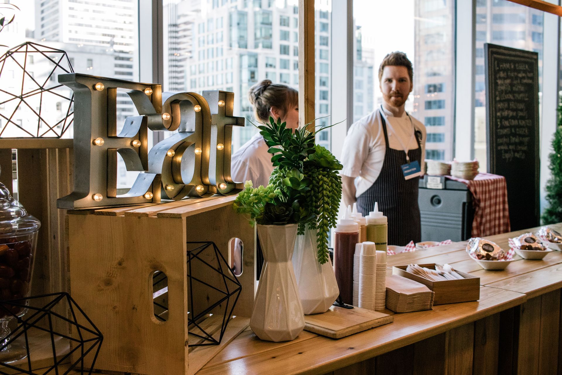 A man and a woman are standing behind a counter with a sign that says `` eat ''.