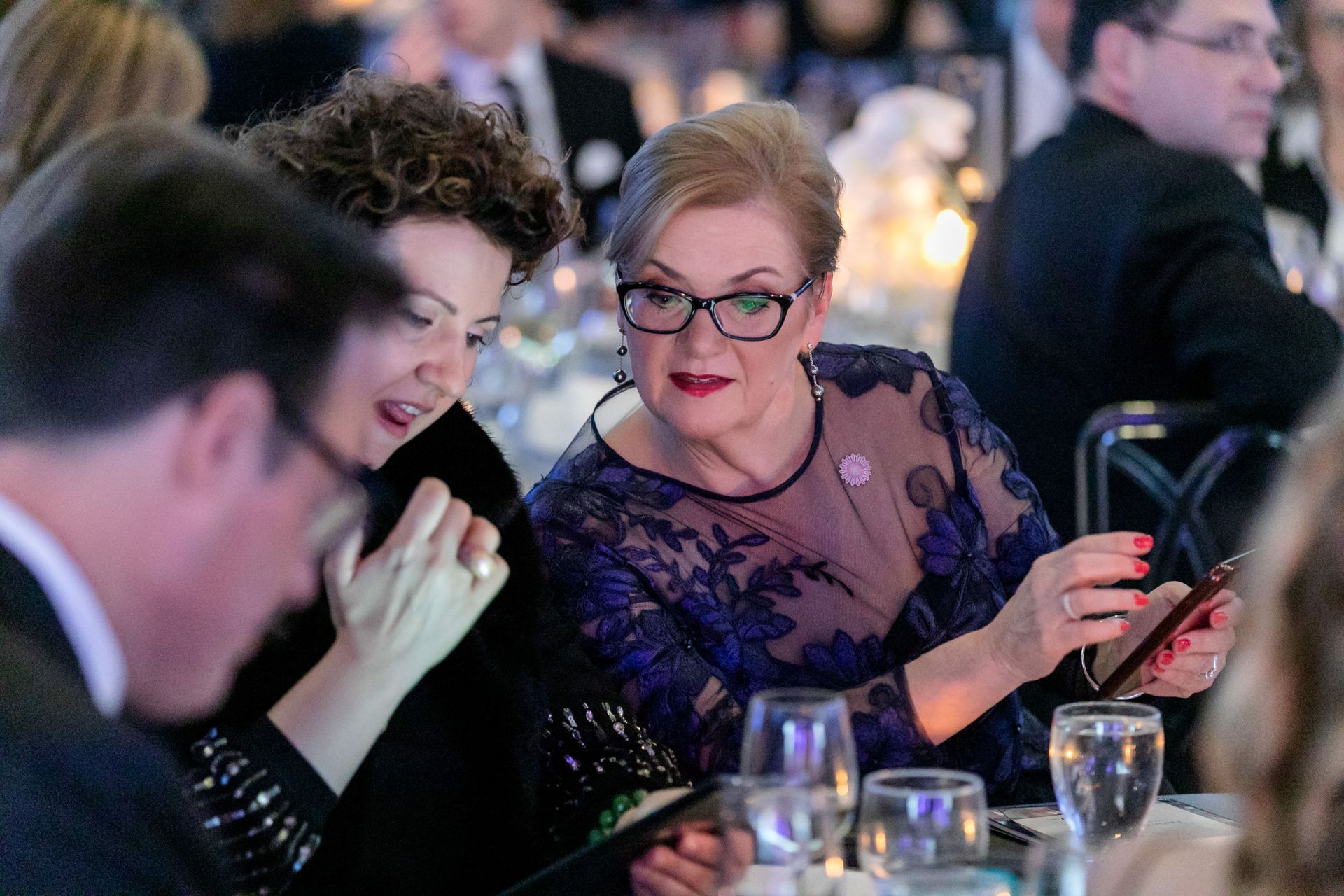A group of people are sitting at a table looking at their phones.