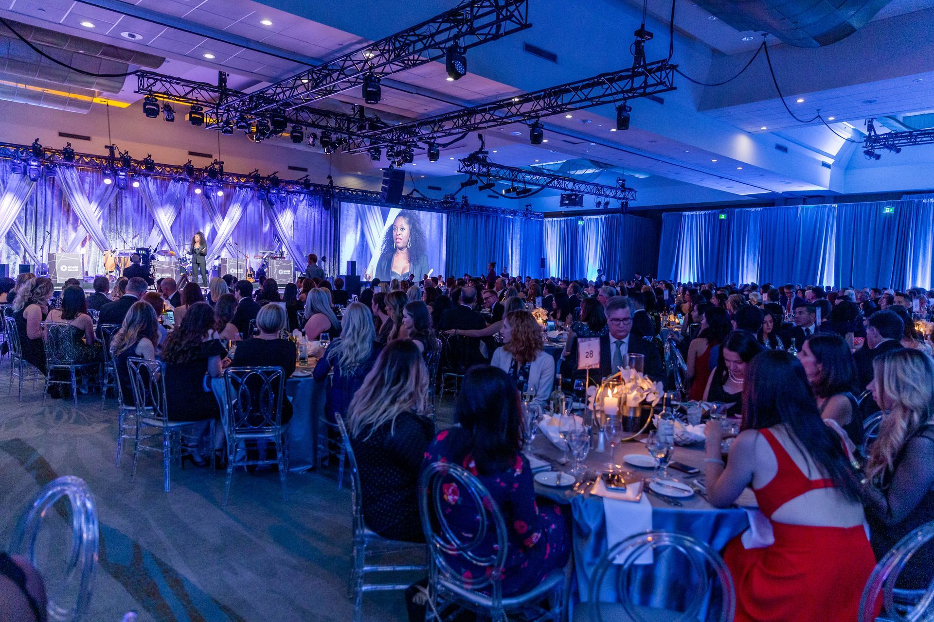 A large group of people are sitting at tables in a large room.