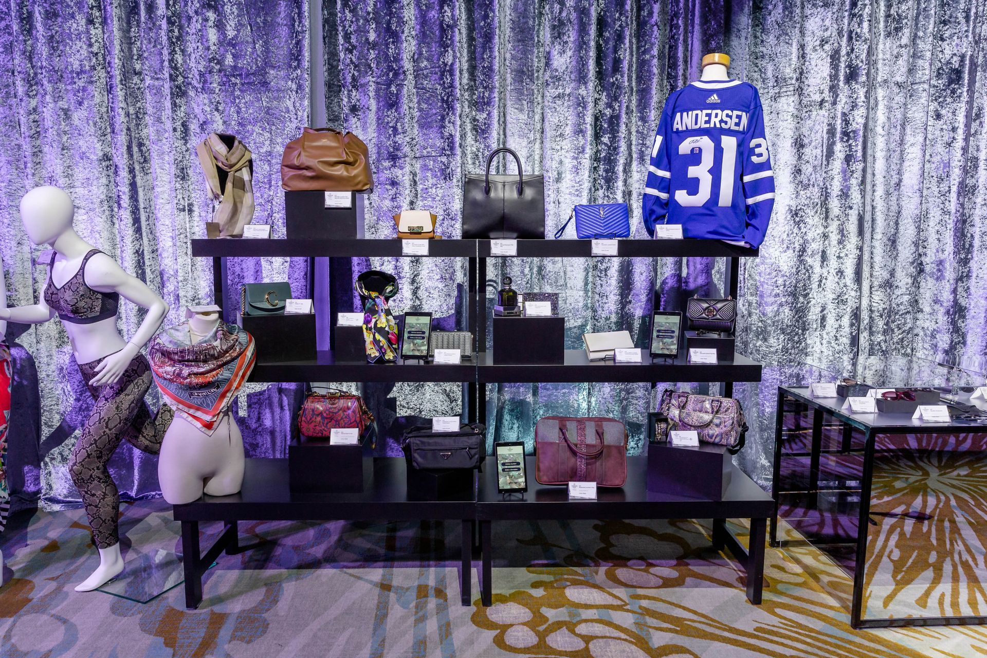 A mannequin is standing in front of a display of handbags and a basketball jersey.