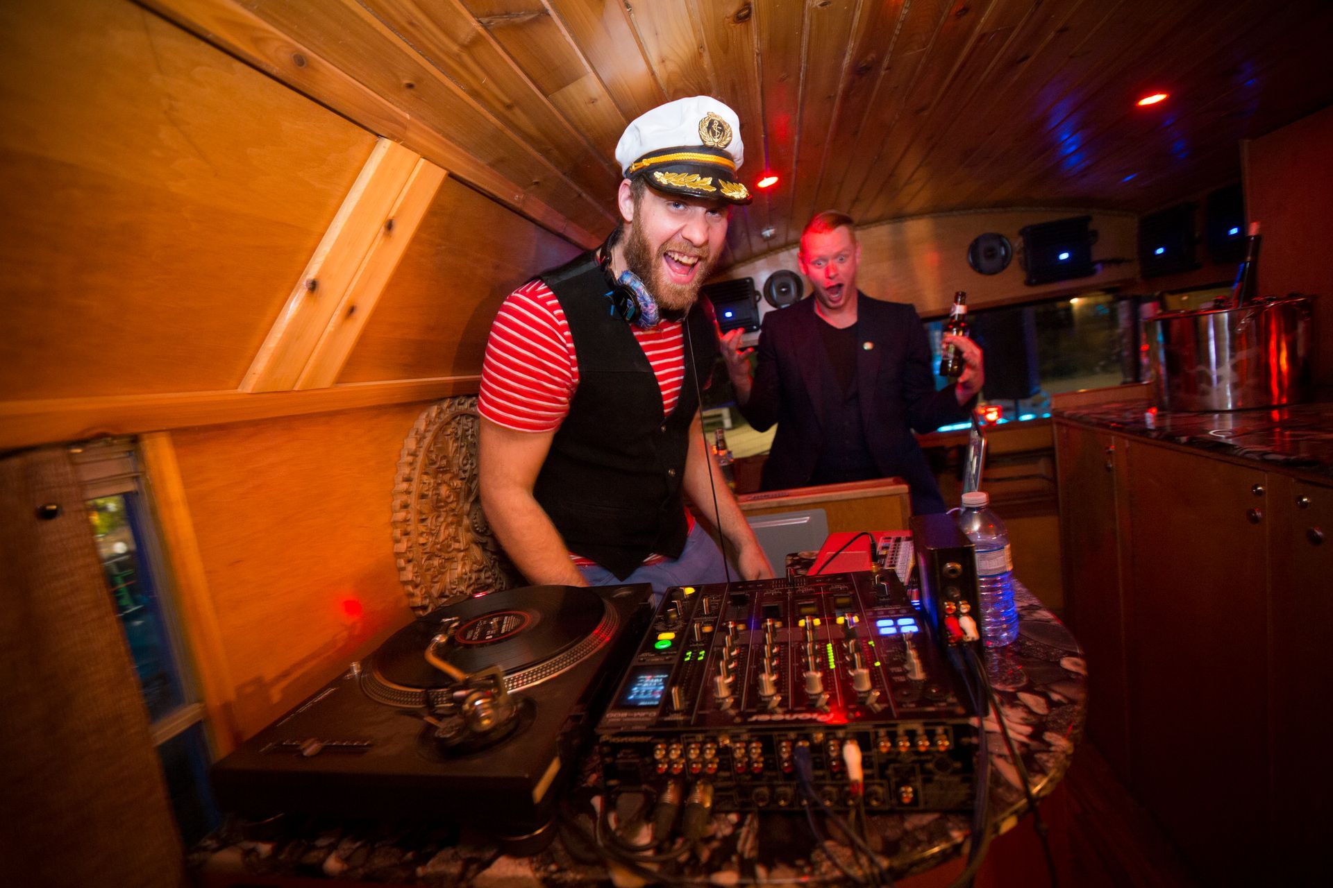 A man in a captain 's hat is standing in front of a dj mixer.