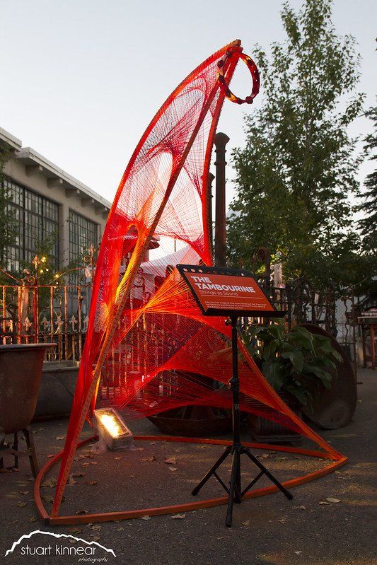 A red sculpture is sitting on a stand in front of a building.