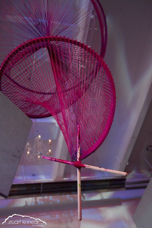 A pink fan is hanging from the ceiling in a room