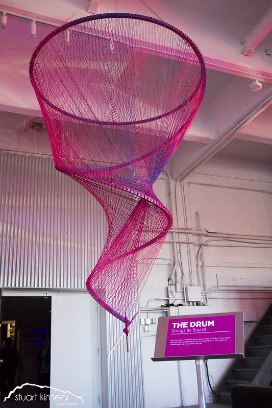 A pink and purple sculpture is hanging from the ceiling of a building.