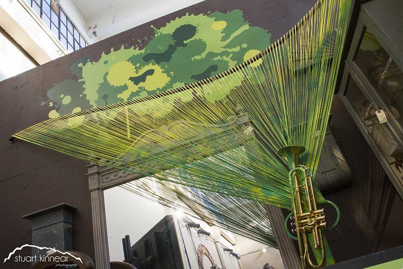 A trumpet is hanging from the ceiling in front of a mirror