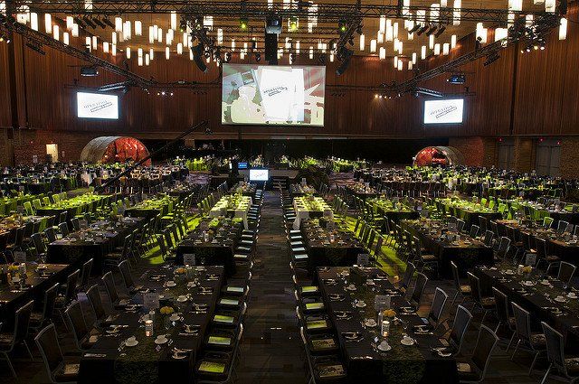 A large room filled with tables and chairs and a large screen.