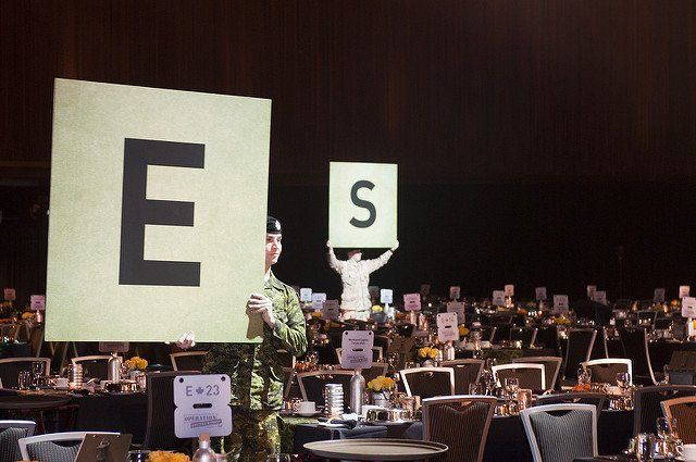 A man in a military uniform is holding a sign that says e and s.