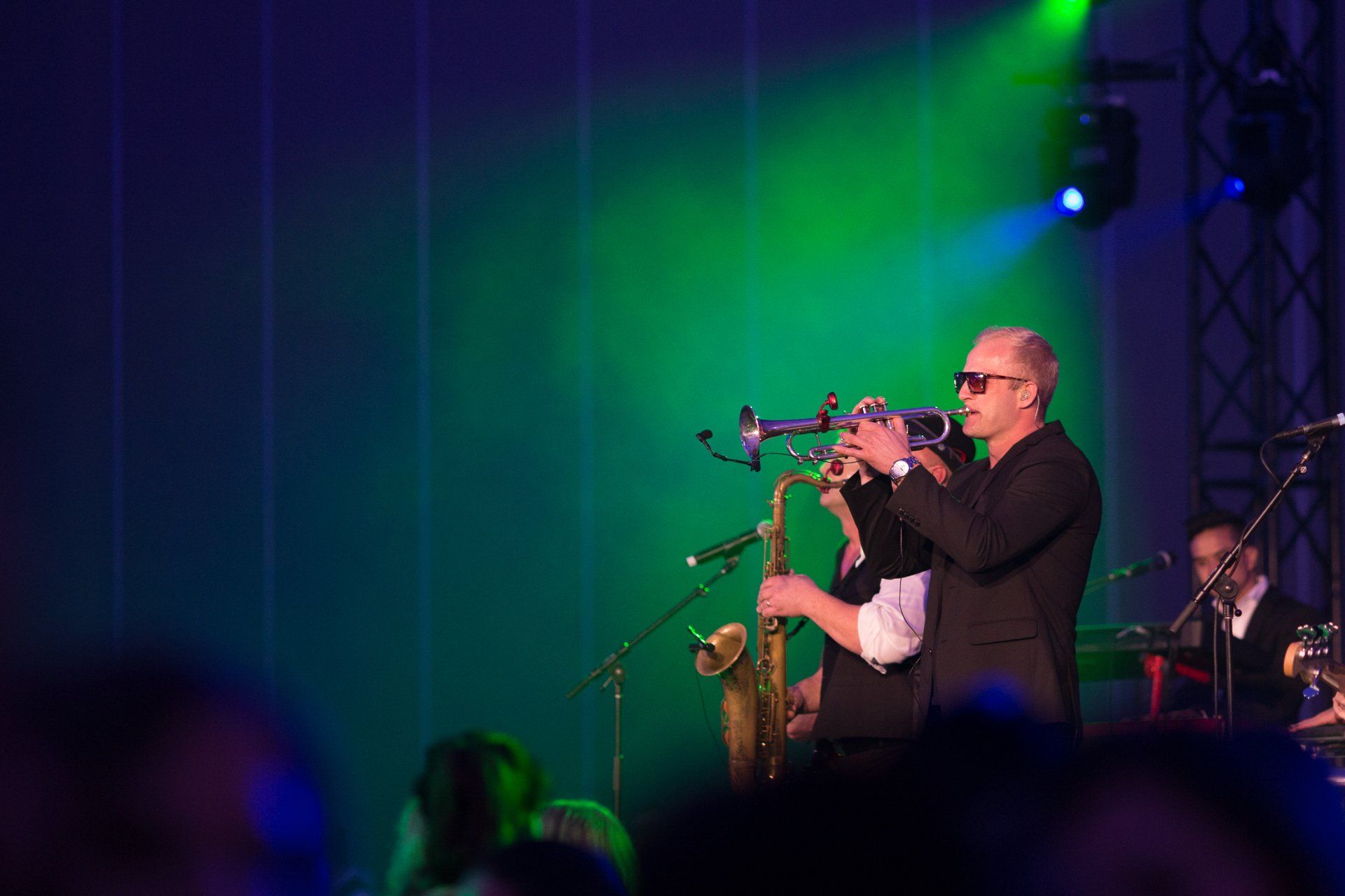 A man is playing a trumpet on a stage in front of a crowd.