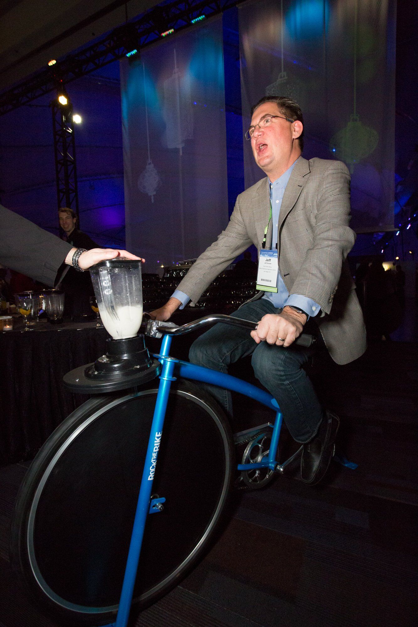 A man is riding a bicycle with a blender attached to it.