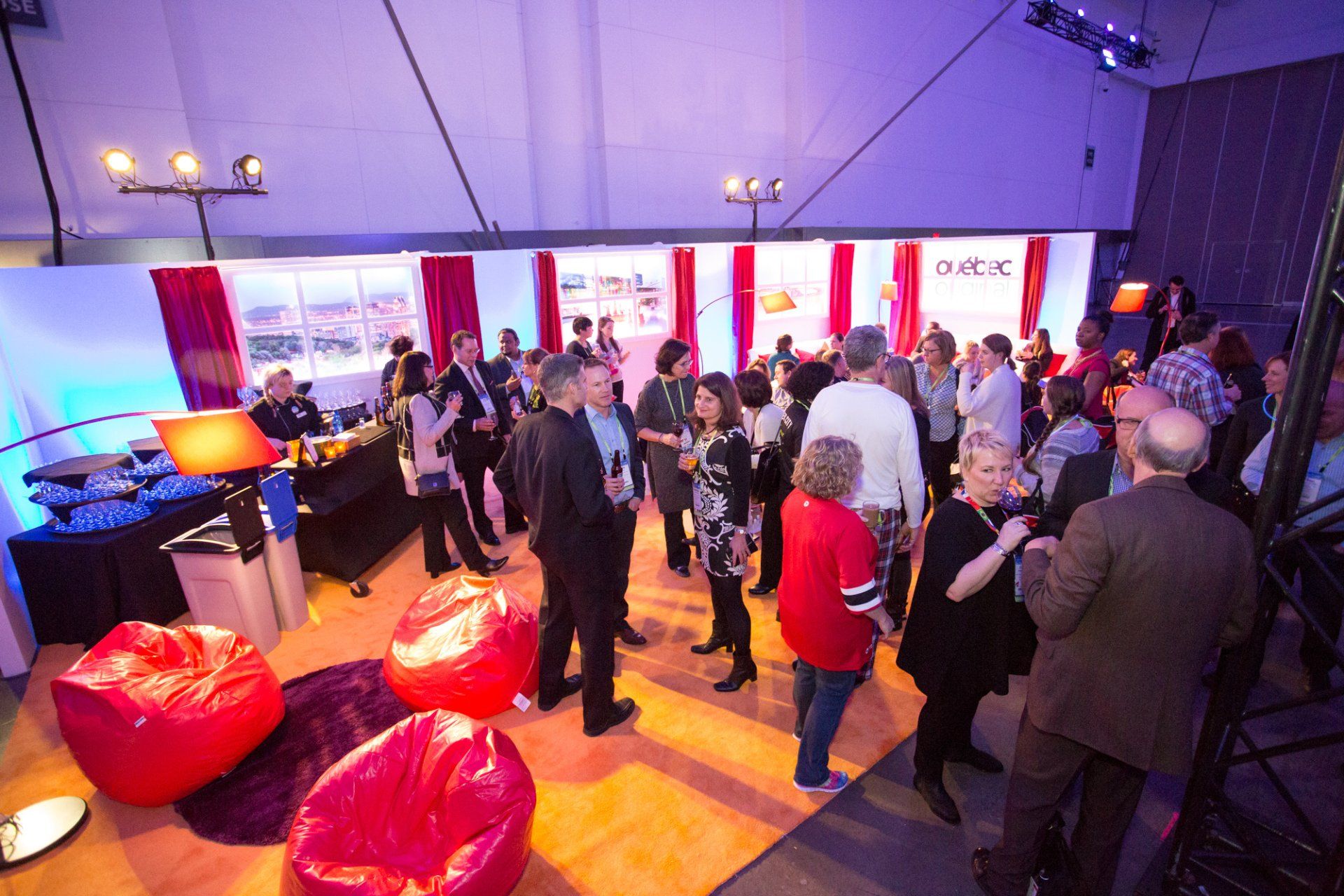 A large group of people are standing in a room with red bean bag chairs.
