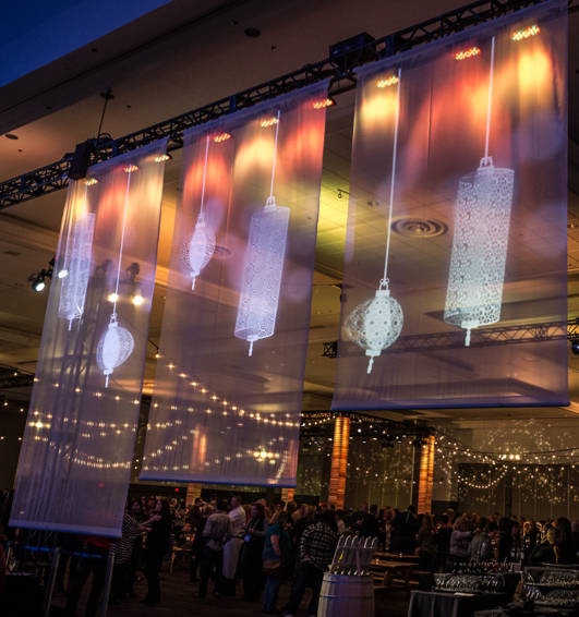 A group of people are gathered in a room with a projector projecting lanterns on the wall