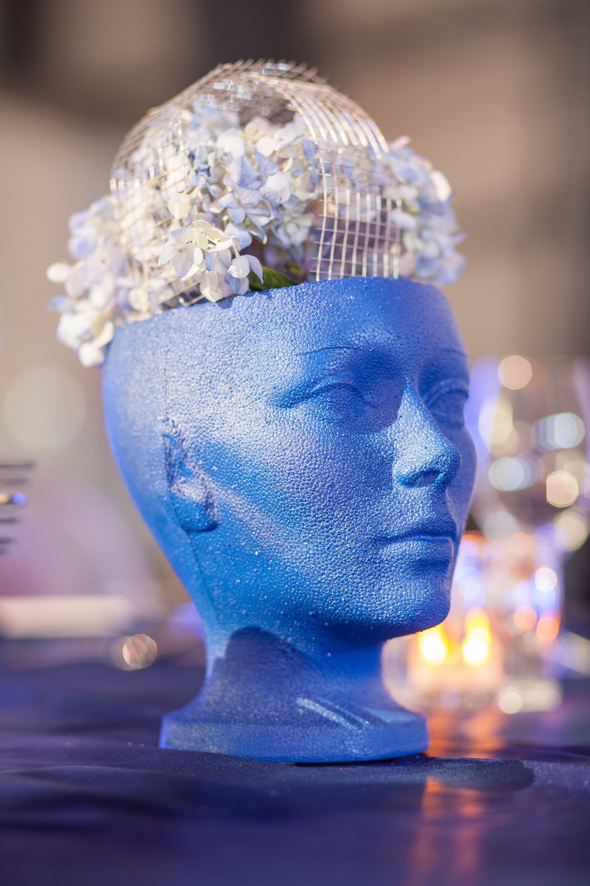 A styrofoam head with flowers in it is sitting on a table.