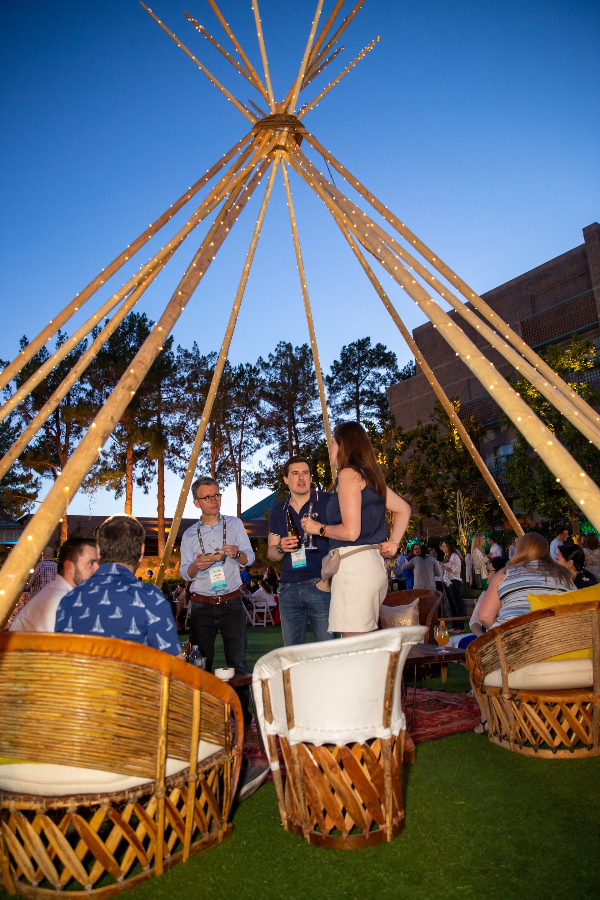 A group of people are sitting in chairs under a teepee.