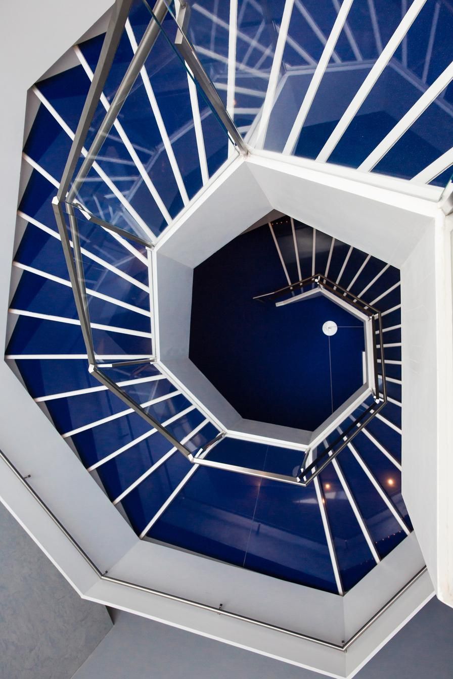 A spiral staircase with blue steps and white railing