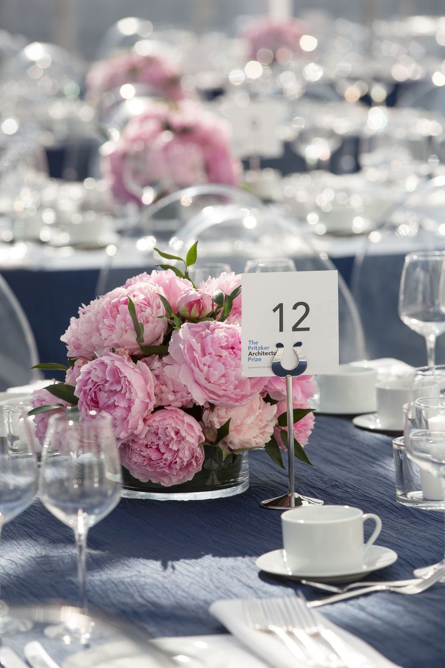 A table with a vase of pink flowers and a table number 12