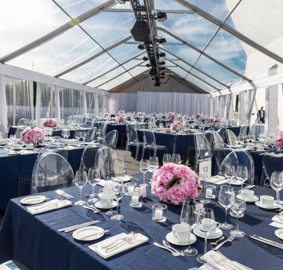 A large tent with tables and chairs set up for a wedding reception