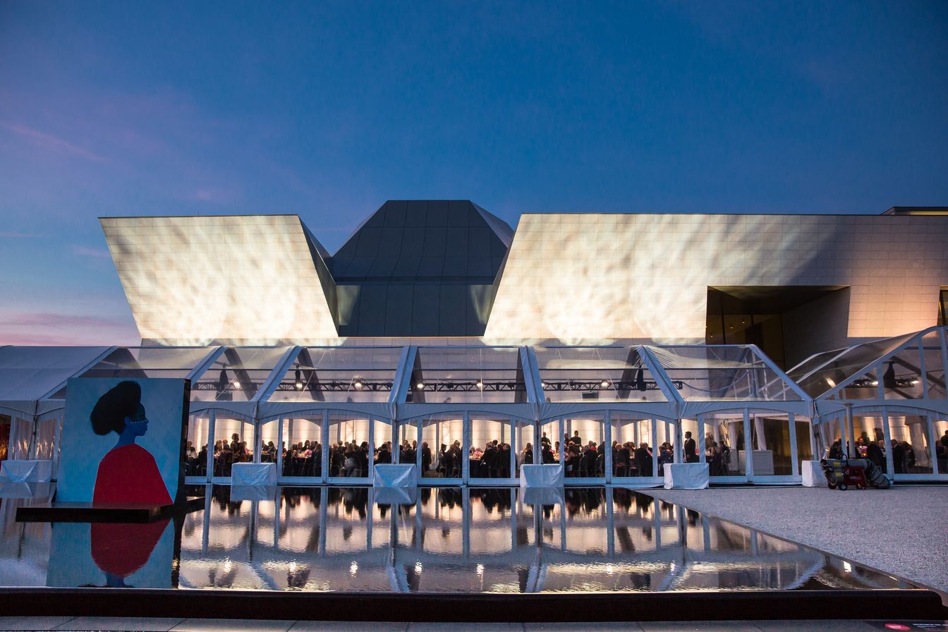 A large building with a clear roof is lit up at night.