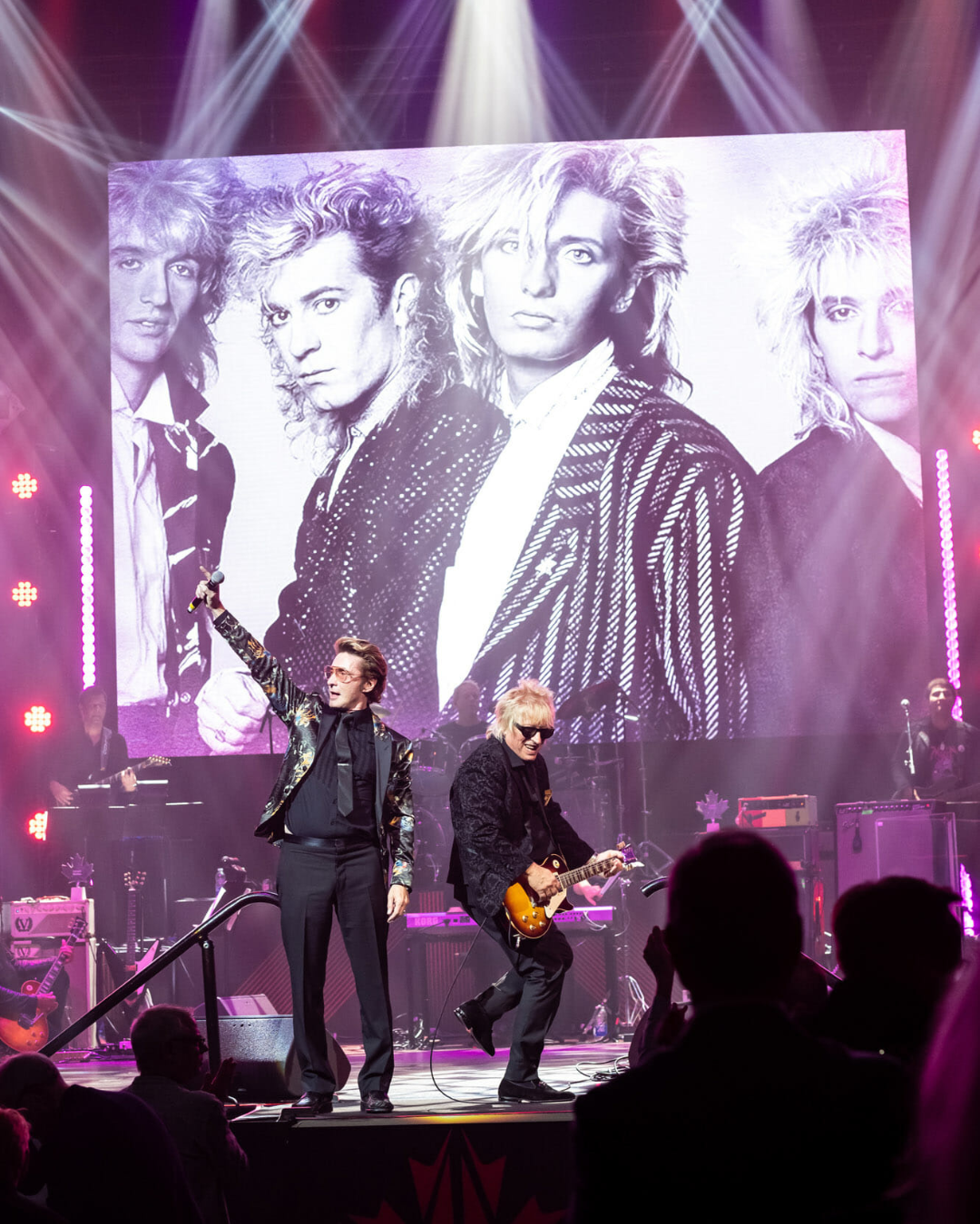A group of men are standing on a stage in front of a large screen.
