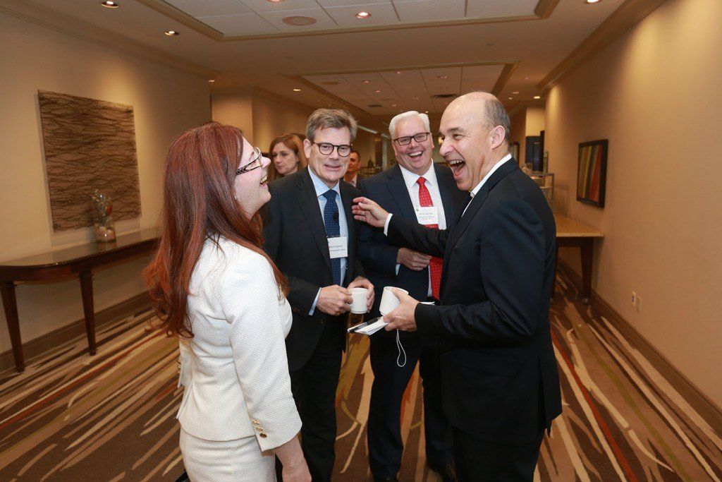 A group of people are standing in a hallway talking to each other.