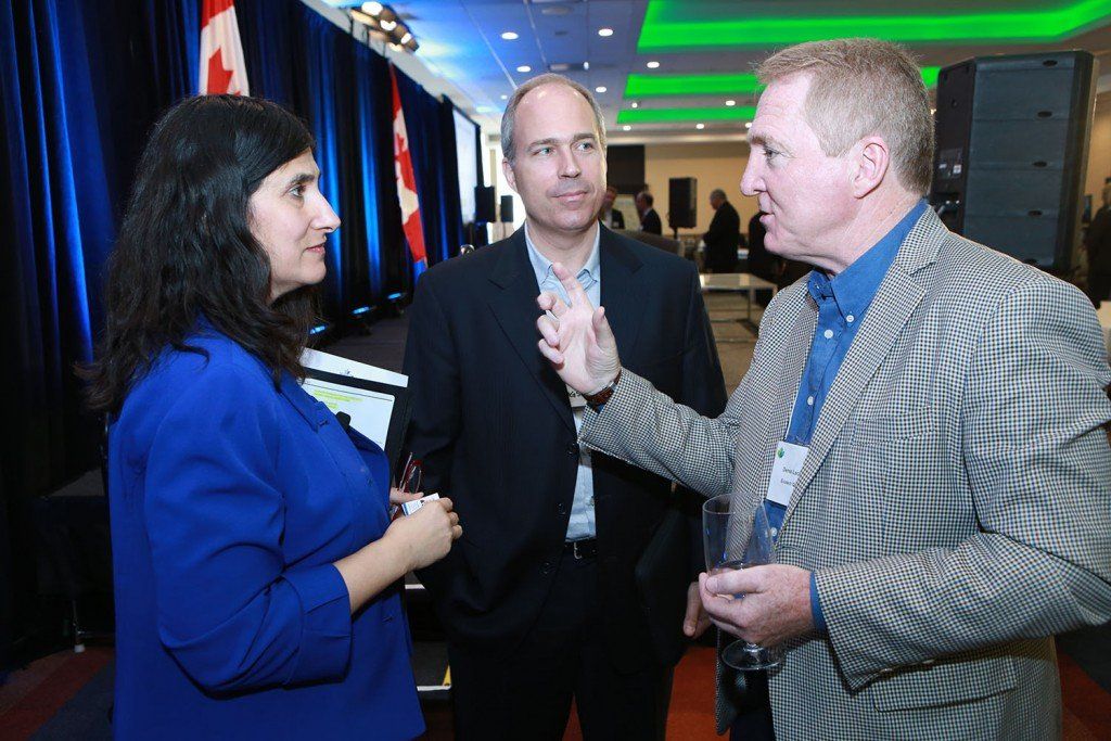 A group of people are standing in a room talking to each other.