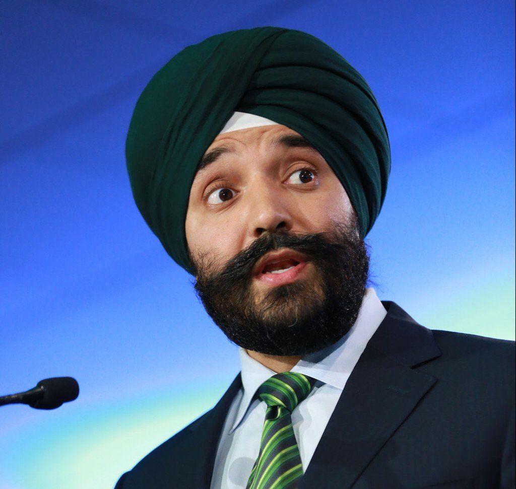 A man wearing a turban and tie is speaking into a microphone
