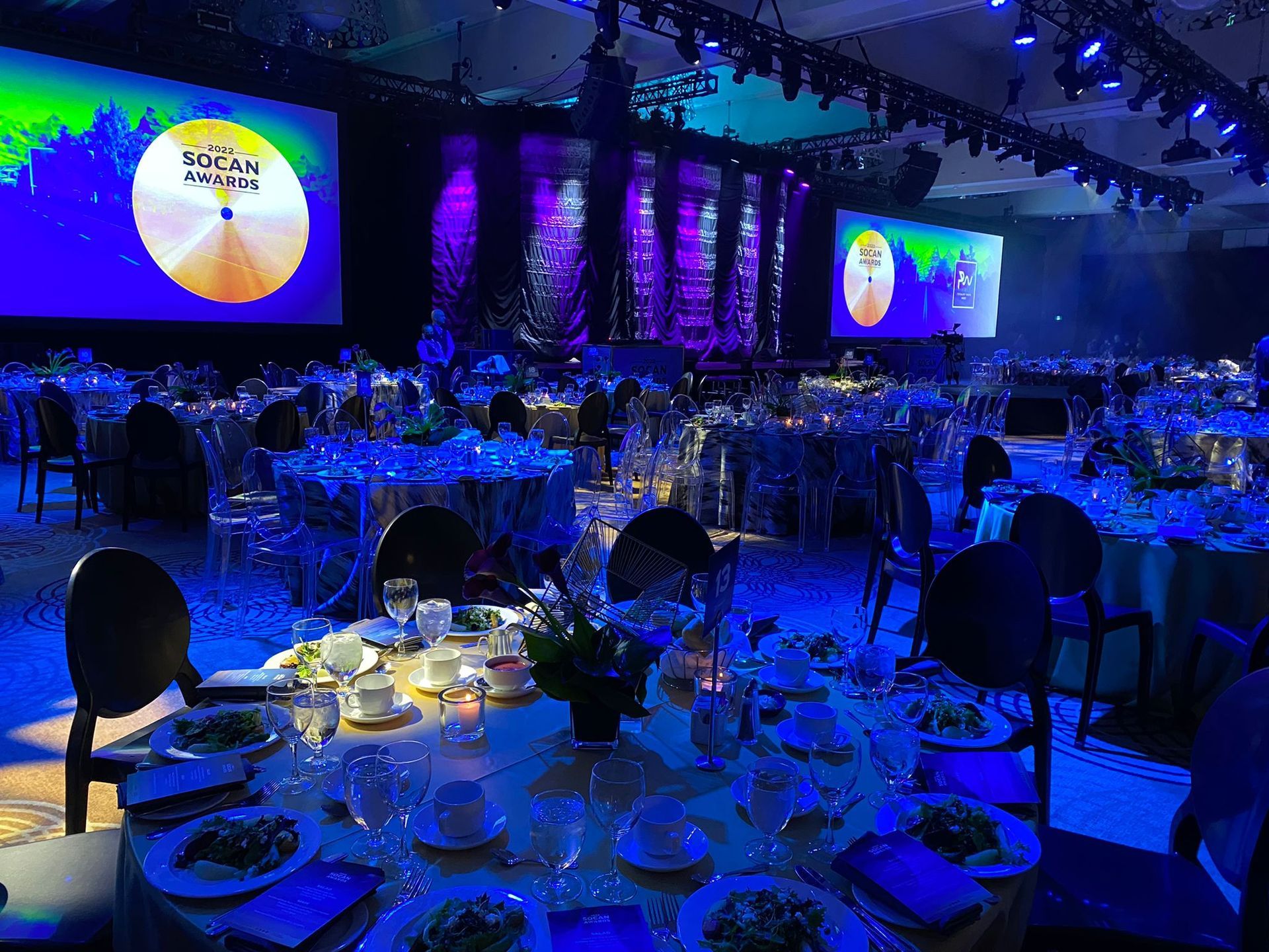 A large room filled with tables and chairs and a stage.