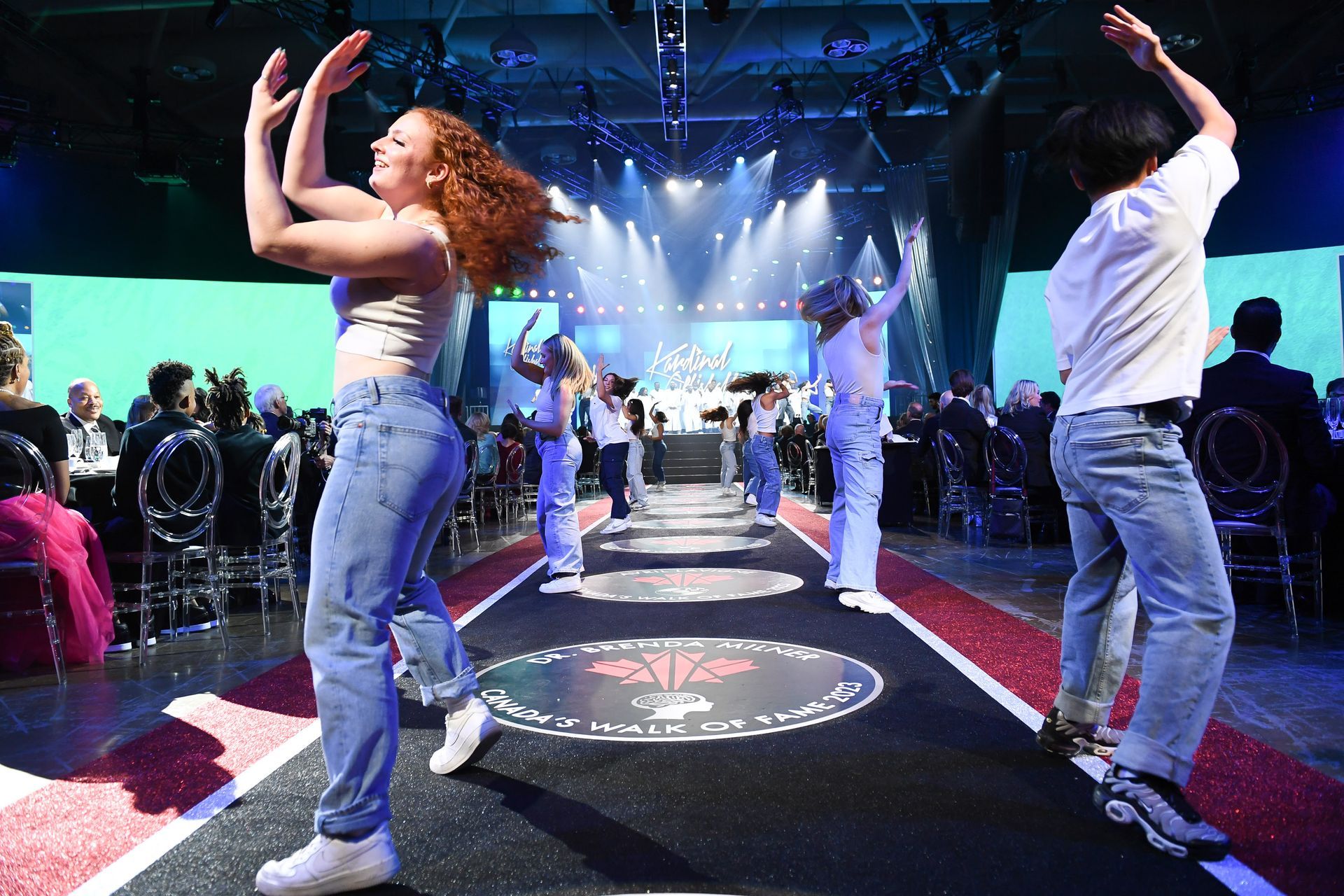 A group of people are dancing on a stage in front of a crowd.