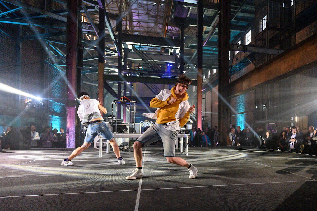 Two men are dancing on a stage in a dark room.