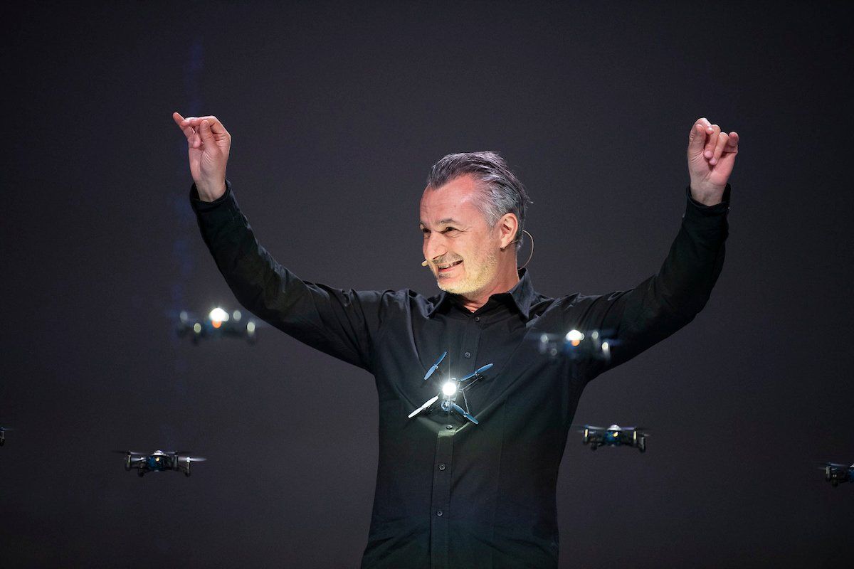 A man in a black shirt is standing on a stage with his arms in the air.