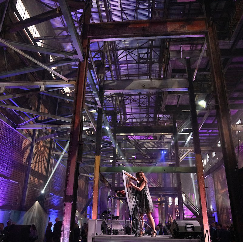 A woman is standing on a stage in a large building with purple lights