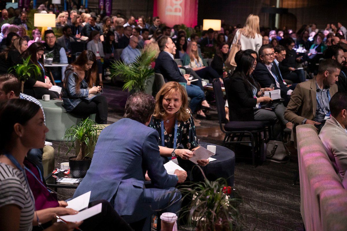 A large group of people are sitting in a room at a conference.