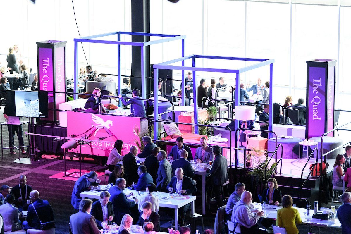 A group of people are sitting at tables in a large room.