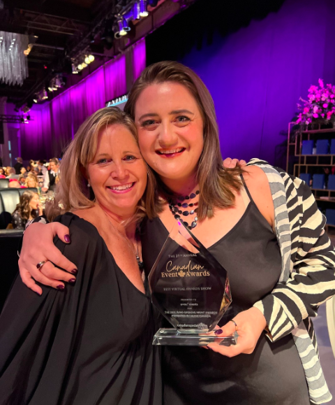 Two women are posing for a picture and one is holding a trophy