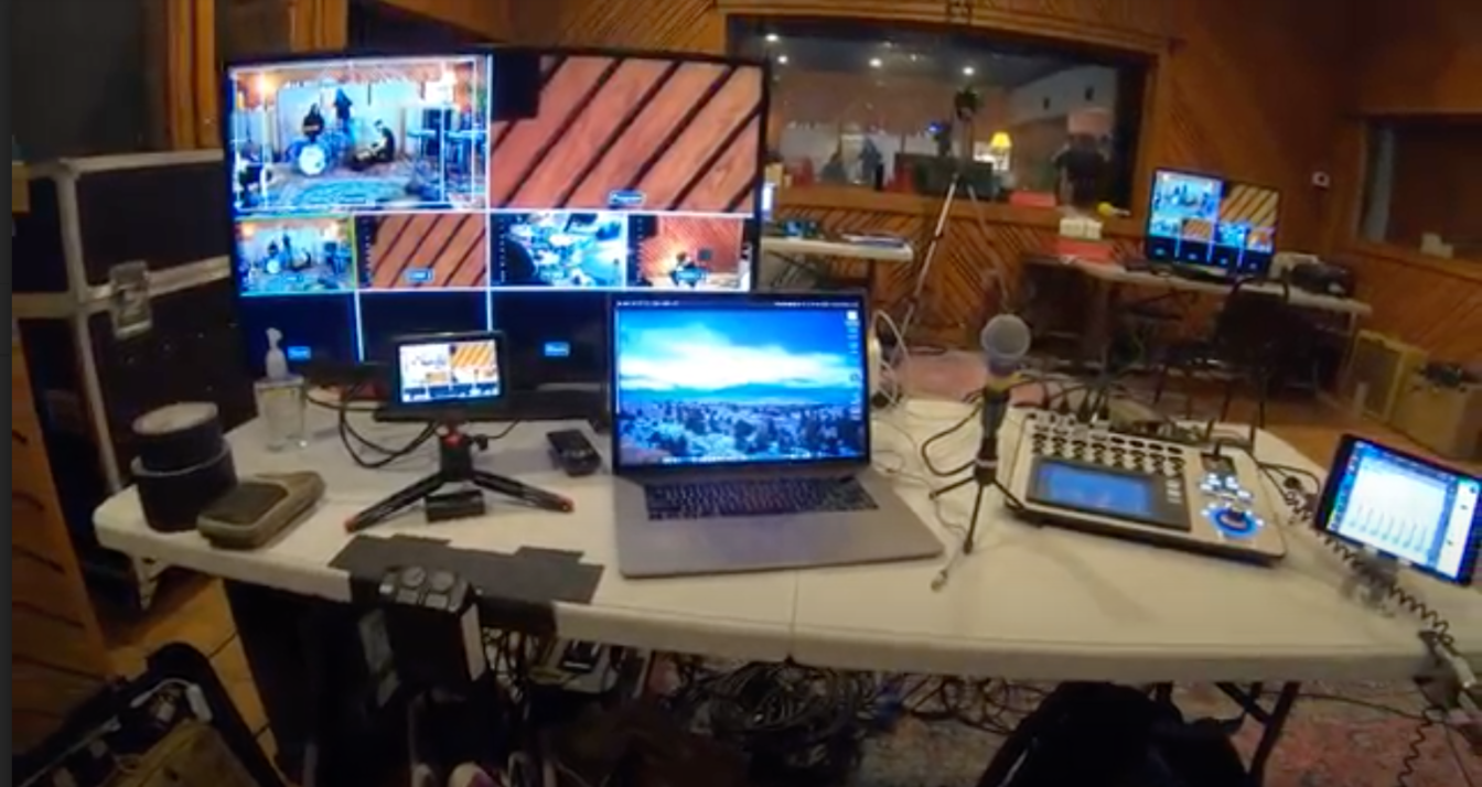 A laptop computer is sitting on a table next to a monitor.