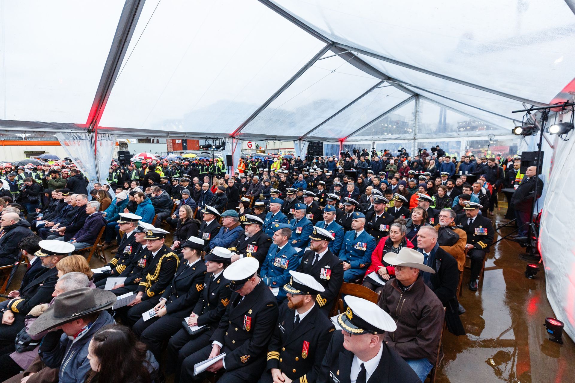 A large group of people are sitting under a clear tent.