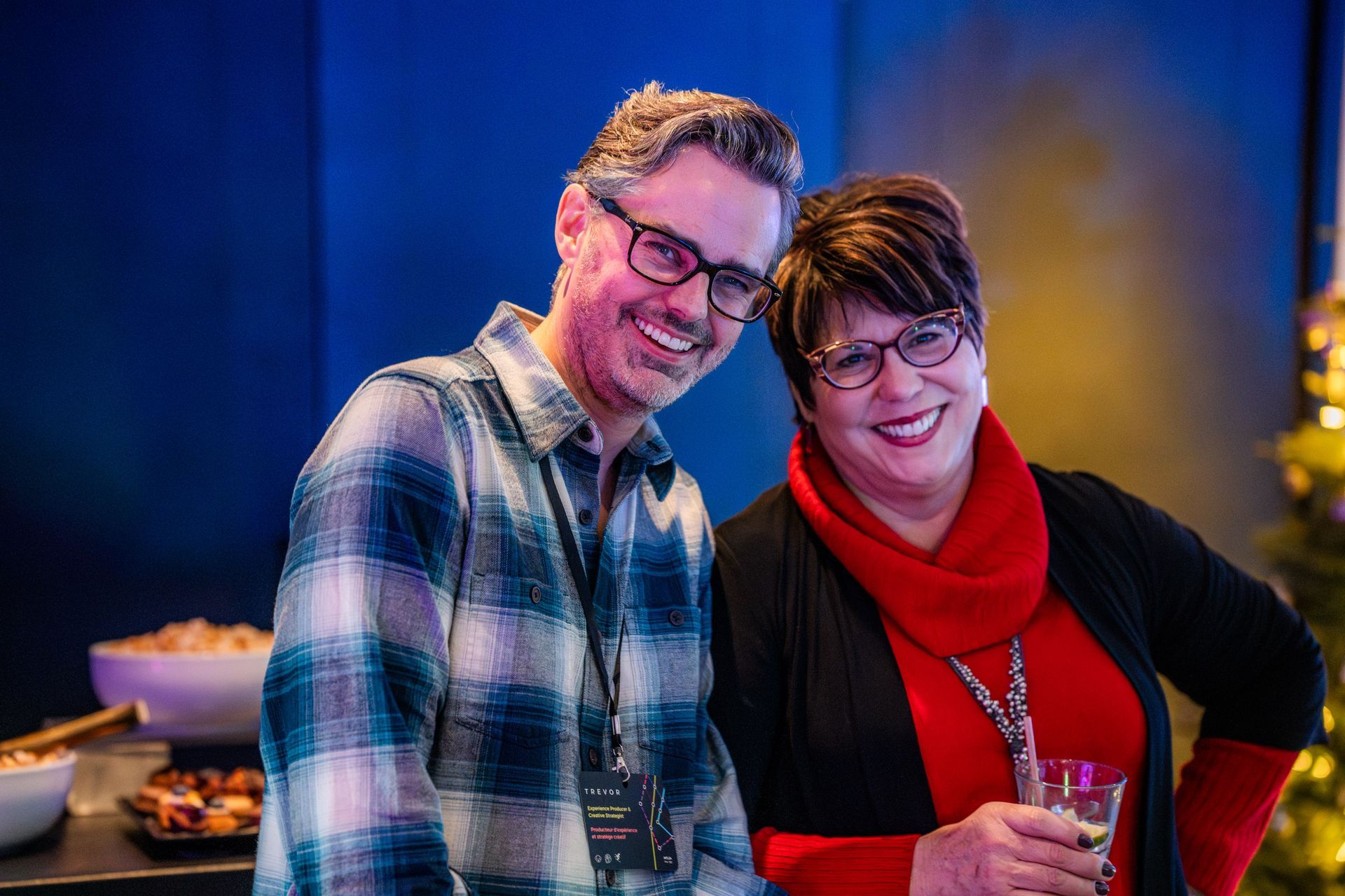 A man and a woman are posing for a picture in front of a christmas tree.