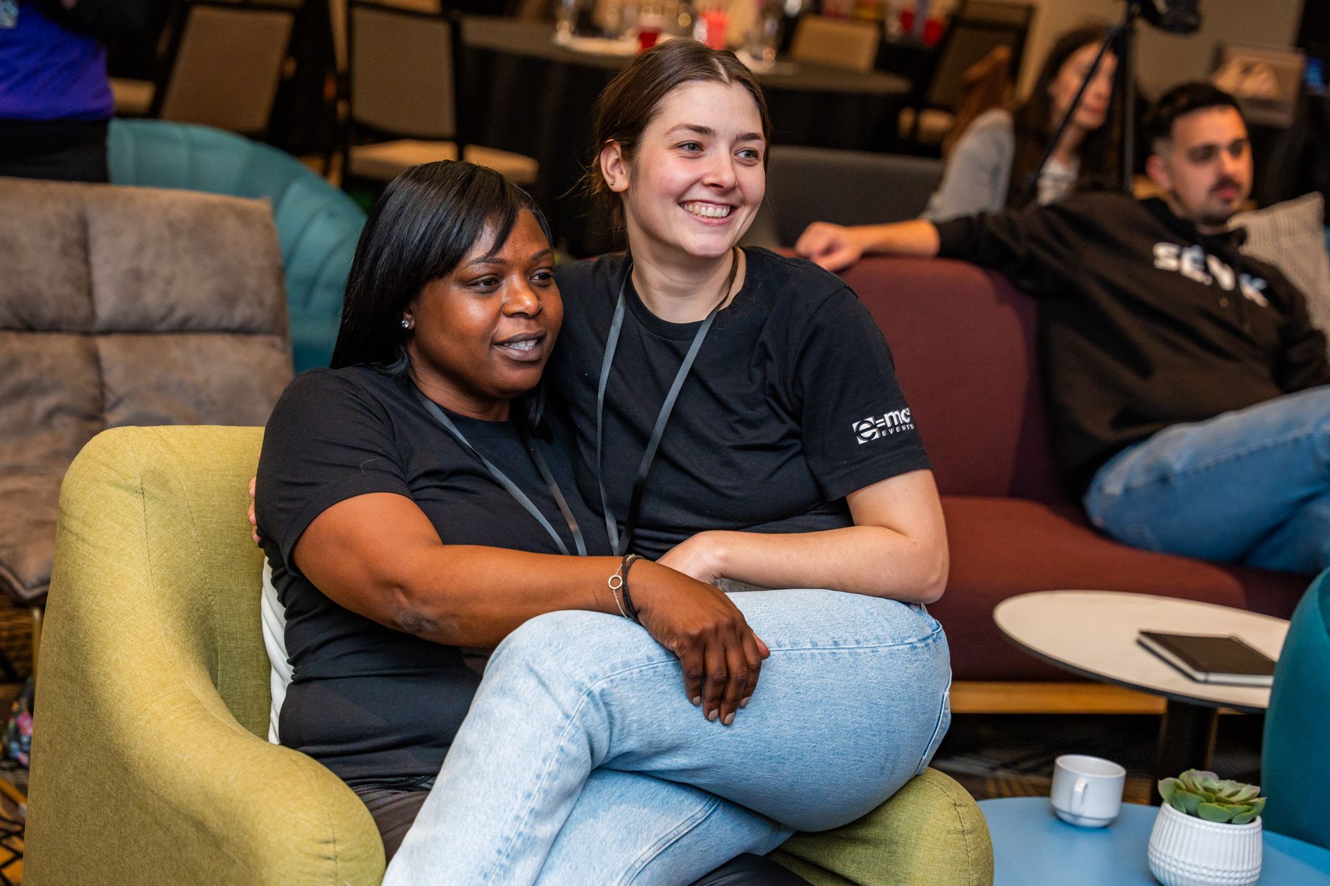Two women are sitting next to each other on a couch.