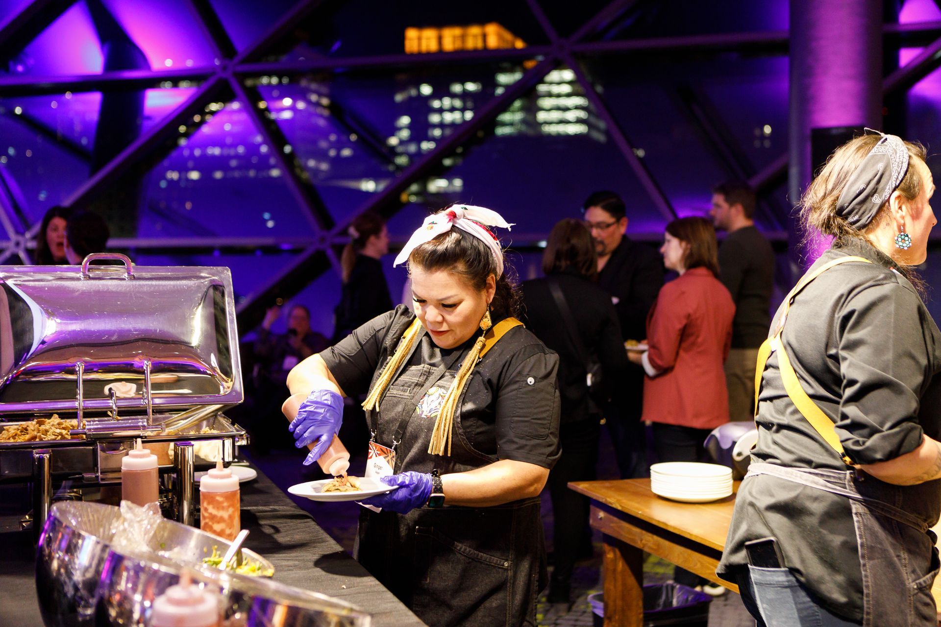 A woman is serving food at a buffet table in a restaurant.
