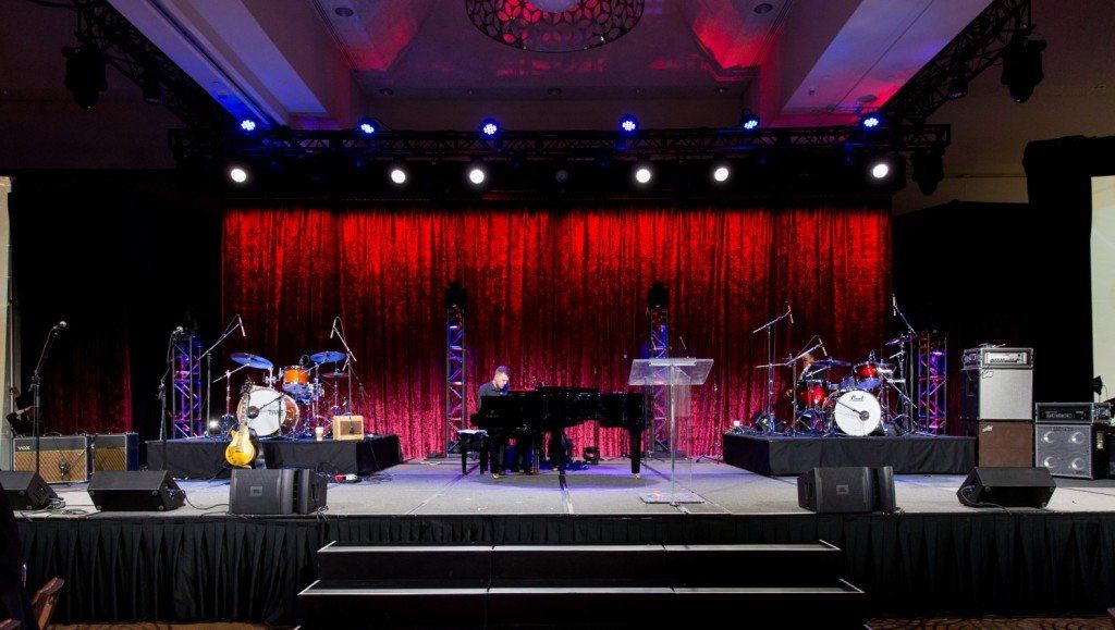 An empty stage with a piano , drums , and other musical instruments.